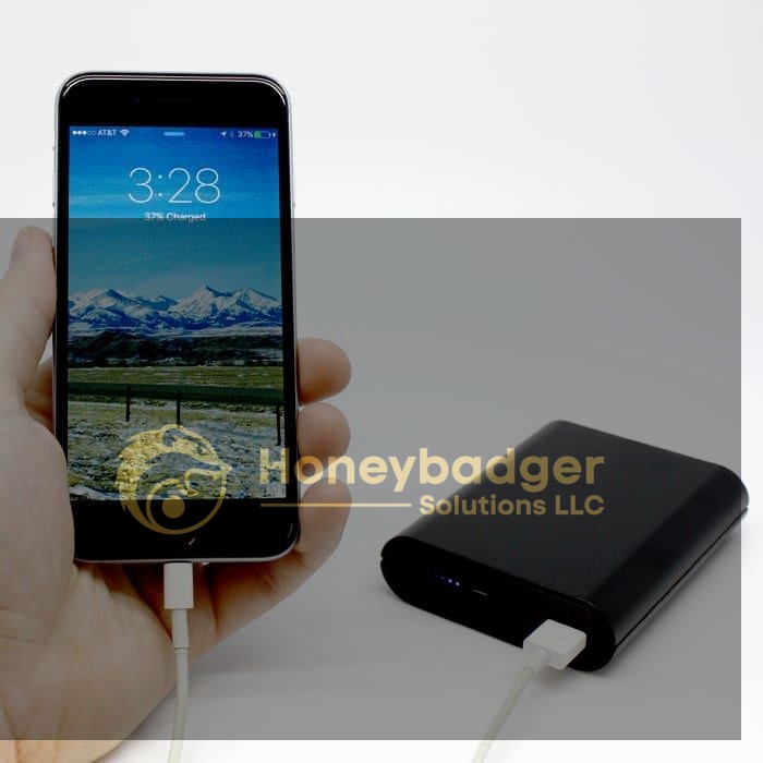 A hand holds a smartphone displaying 37% battery at 3:28, connected to a black power bank via a white cable.