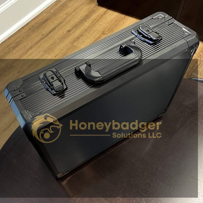 A closed black hard-shell case with metal clasps resting on a dark wooden table.