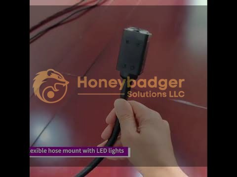 A hand holds a flexible hose mount equipped with LED lights, displayed against a polished wooden floor.