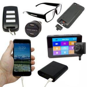 Components of the LawMate Surveillance Kit including a key fob, glasses, phone case, car charger, smartphone, and portable power bank.