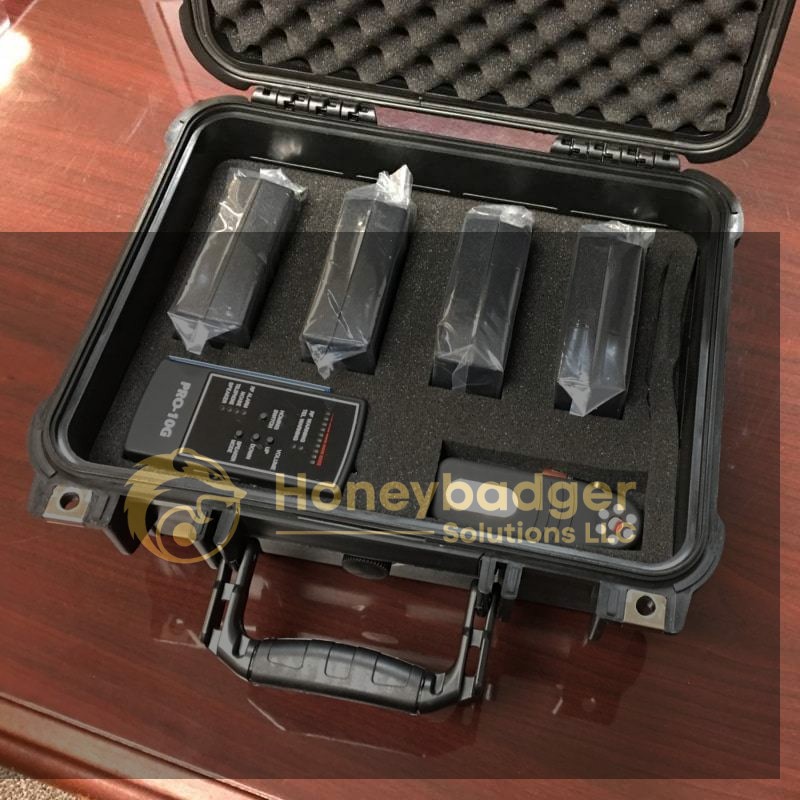 An open black hard case with foam inserts containing the Rapid Deployment Eavesdropping Kit, including four devices and a controller.