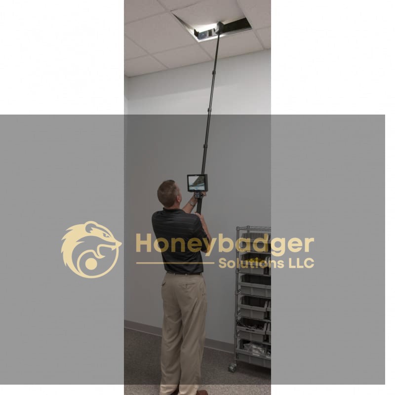 A person using a VPC 2.0 Video Pole Camera to inspect a ceiling panel while holding a monitor for the live feed.