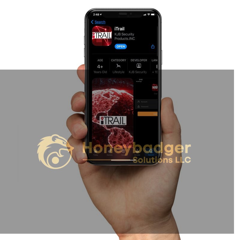 A hand holds a smartphone displaying the iTrail app page from KJB Security Products, Inc. with a globe graphic.