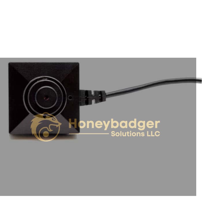 A compact, square black security camera with a central lens and attached black cable.