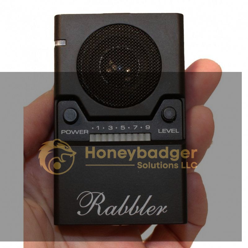 A hand holds the Rabbler Noise Generator, a small black device with a speaker, power and level buttons, and a dial numbered 1–9.