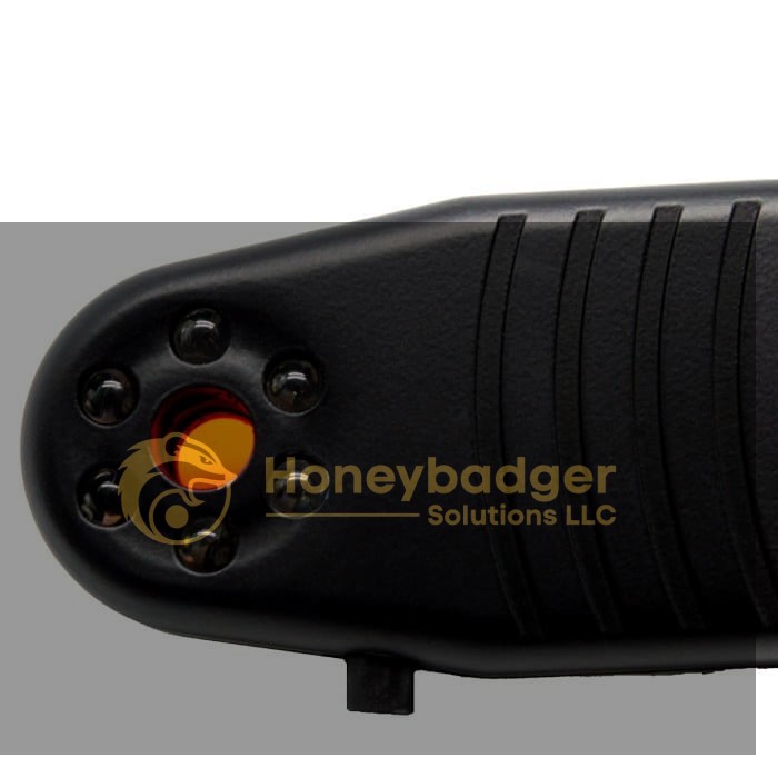 Close-up view of the Spy Finder Pro, a black security device with a textured surface and a circular orange light surrounded by six small lenses.