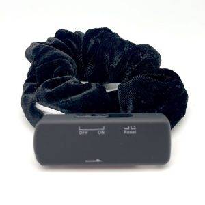 Black velvet scrunchie with a rectangular recording device attached, featuring an off/on switch and reset button.