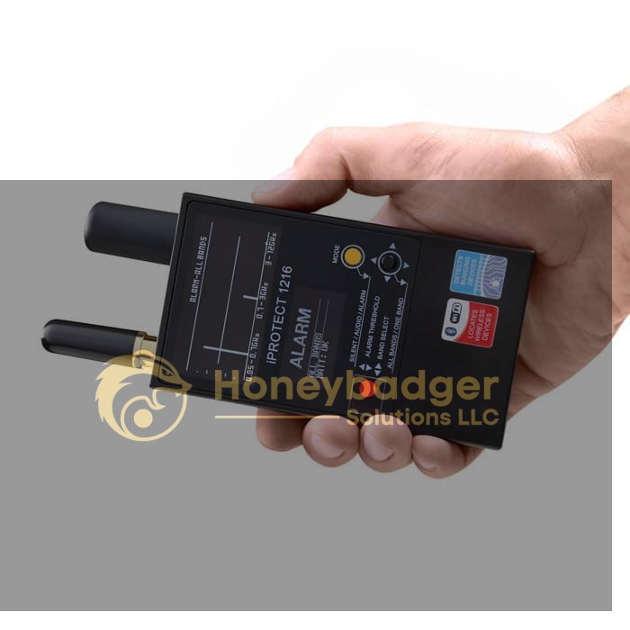 A hand holds a Detection and Counter Surveillance Kit with two antennas, buttons, switches, and indicator lights on the front panel.