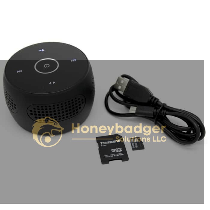 A compact black Bluetooth speaker with touch controls, USB charging cable, and a Transcend microSD card.