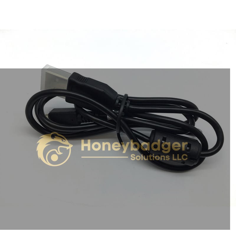 Black power cable with a three-prong plug and cylindrical ferrite bead, coiled and secured with a twist tie.