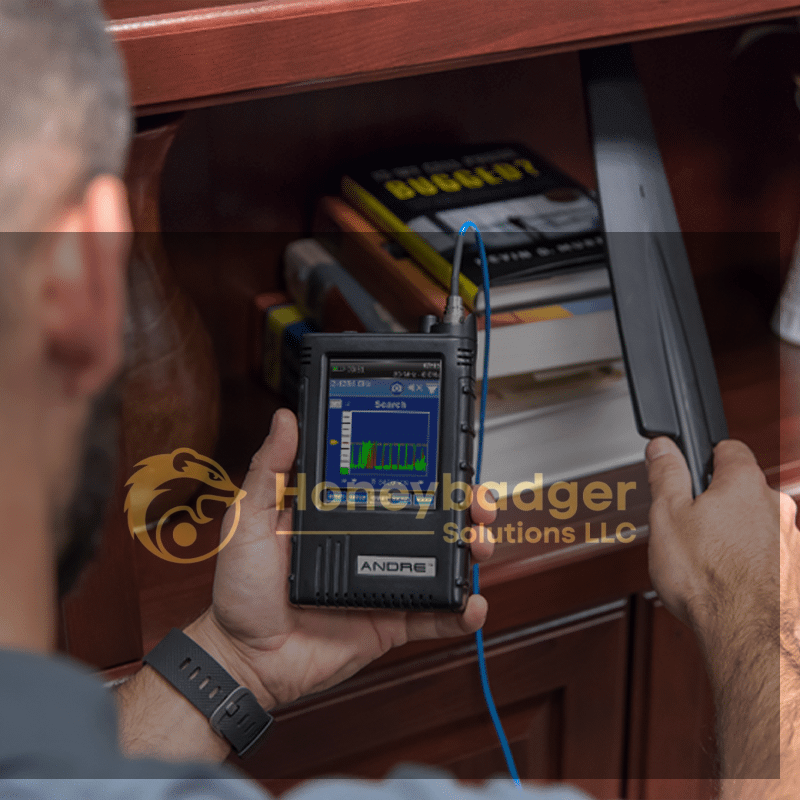 A person uses the Andre Advanced handheld device with a screen and wand attachment to scan books on a shelf.