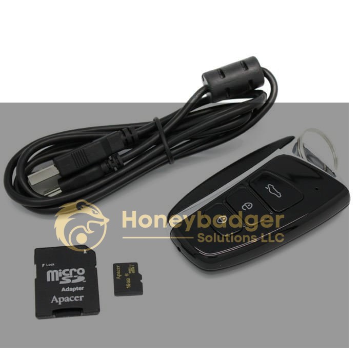 A black keychain hidden camera, a microSD card, and an SD adapter arranged on a white surface.