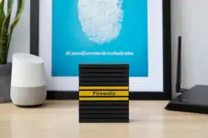 Firewalla Cyber Security Firewall with a fingerprint poster and smart speaker on a desk.