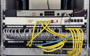A server rack containing network switches and a Firewalla Gold Pro Rack Mount with connected Ethernet cables.