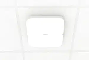 Firewalla Access Point 7 mounted on a white ceiling tile, with a small blue indicator visible on its side.