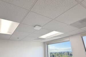 Ceiling featuring a Firewalla Access Point 7 and white acoustic tiles with fluorescent lights.