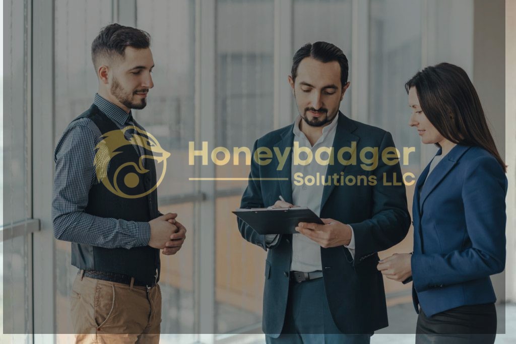 Three business professionals in formal attire discussing strategies while one man writes on a clipboard.