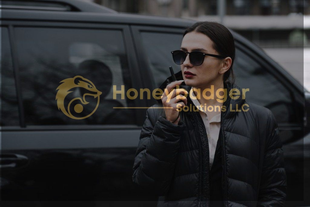 A female protection agent wearing sunglasses and a black puffer jacket, using a communication device near a black vehicle.