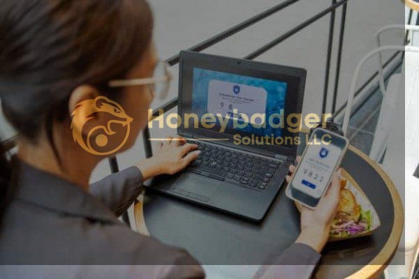 Individual interacting with a laptop and smartphone while seated at a table with food.