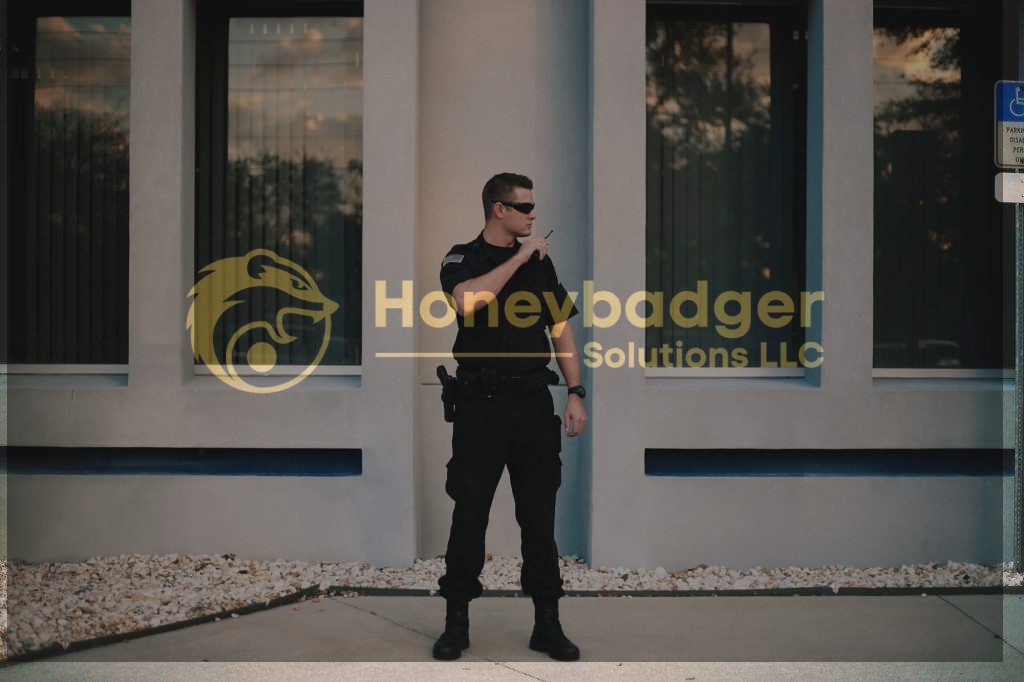 A residential security guard wearing a black uniform and sunglasses, standing outside a building.