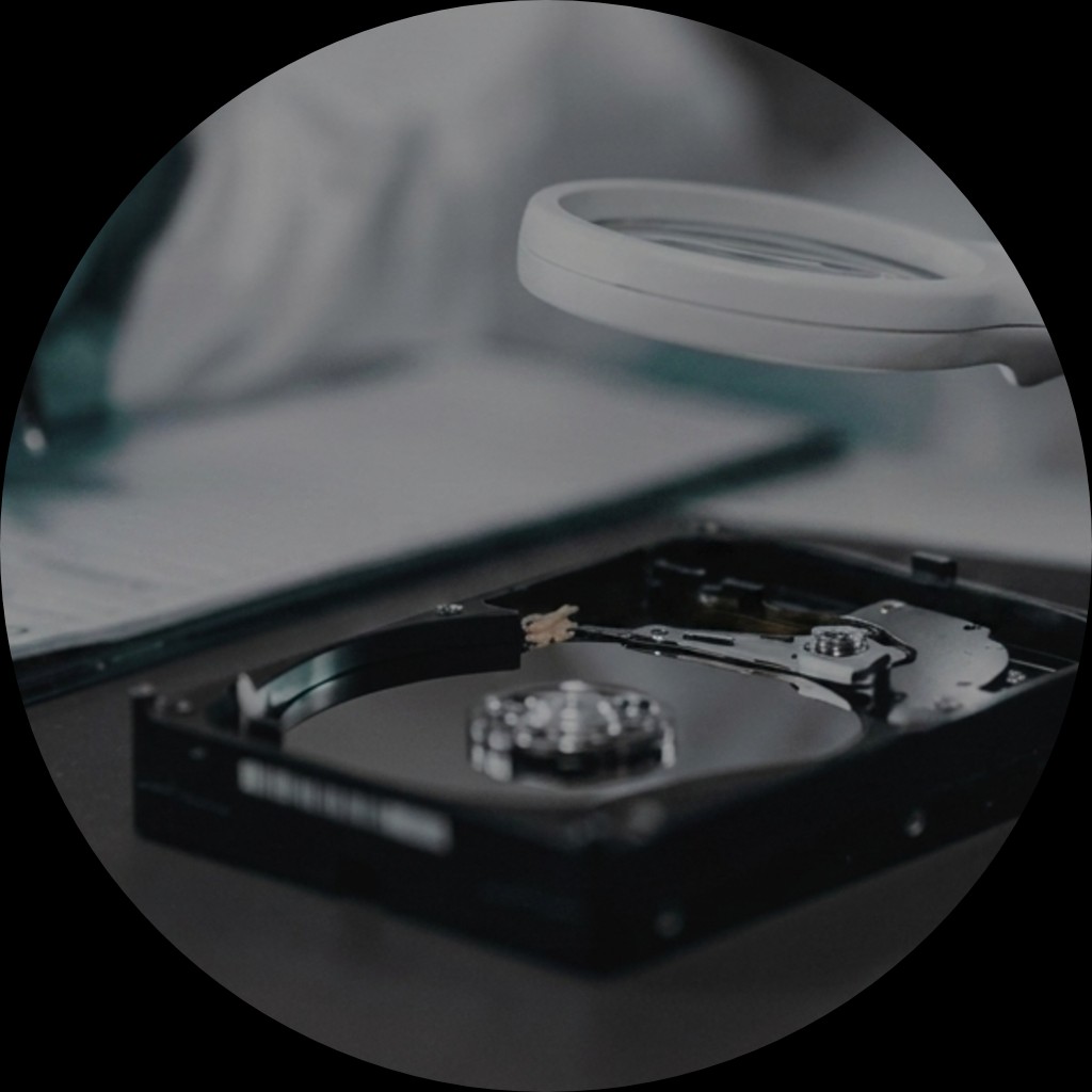 Forensic examiner inspecting a hard drive with a magnifier in a lab