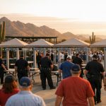 Stadium security officers screening fans at the entry gates of an Arizona ballpark at sunset